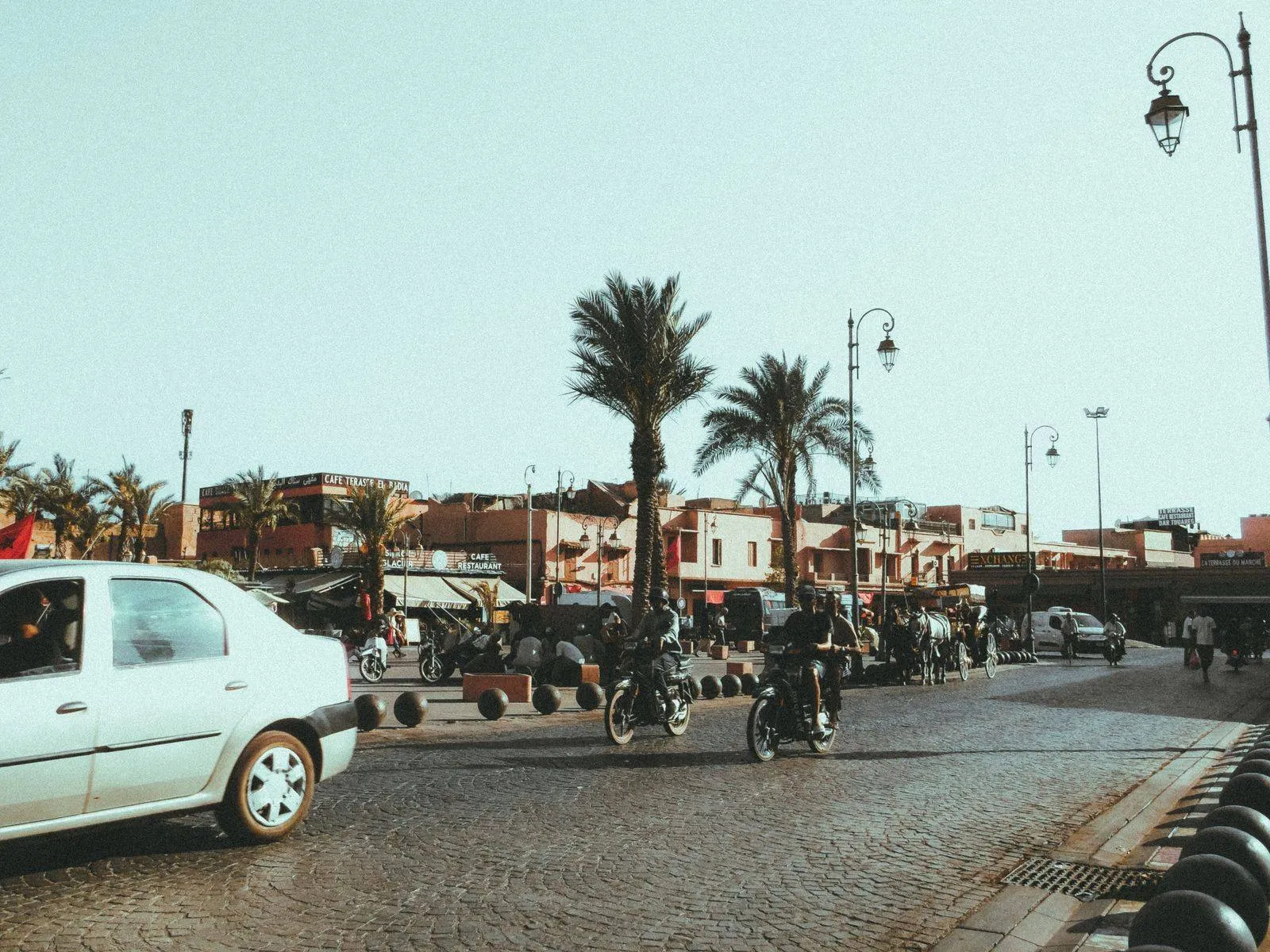 Ulica w Marrakeszu z jadącymi motocyklami i palmami
